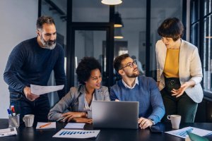 Equipo de empresas mirando notebook y sonriendo